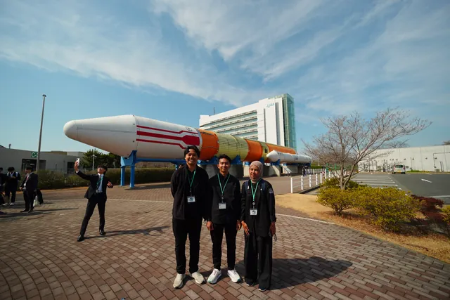 Anggota tim di depan roket pajangan di Tsukuba Space Center